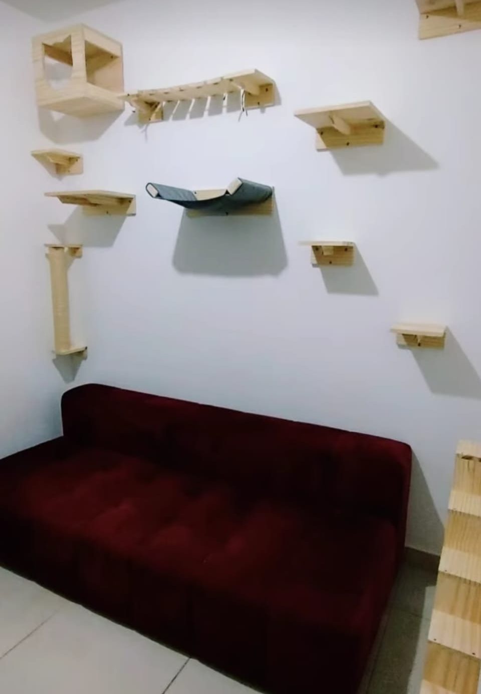 Prateleiras, ponte e rede instaladas na parede logo acima do sofá da sala